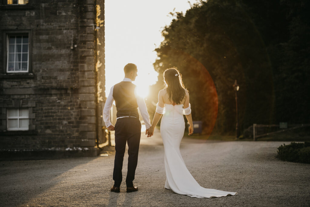 Cinematic Wedding Photography- Wedding couple walking hand in hand at sunset in silhouette.