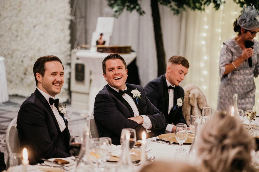 Bride and groom at the top table during the wedding meal call, captured with natural lighting and joyful expressions.