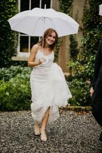 Bride under an umbrella having the craic on her wedding day 