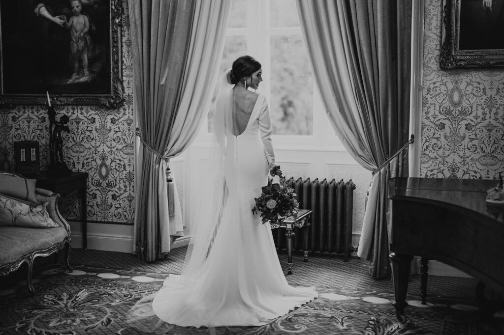 Bride looking over her shoulder in front of window at Cabra Castle. Stunning Black and white by Darren Byrne photography
