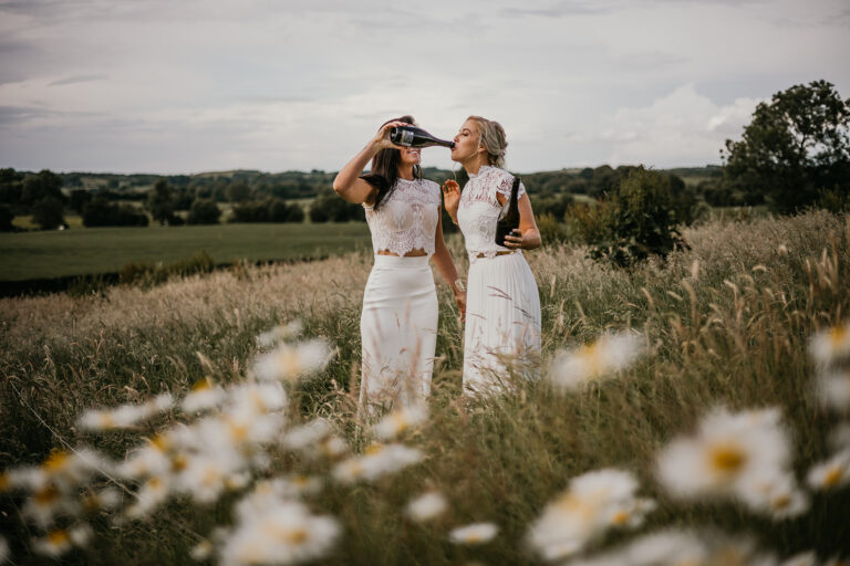 One bride drinking champagne while the other holds the bottle. two brides wedding portraits ireland