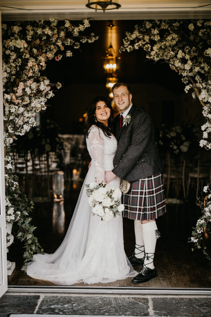 Bride and groom standing under a floral wedding arch